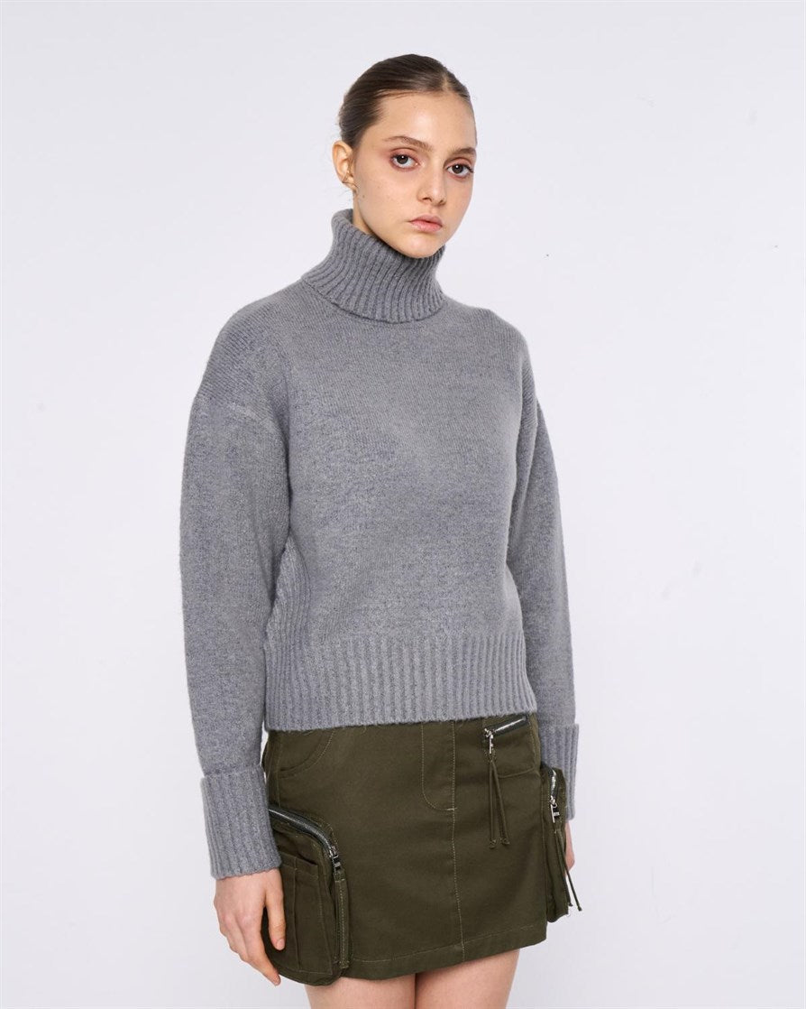 MAGLIONE A COLLO ALTO. ORLI A COSTE E DETTAGLI RICAMI LUNGO LE MANICHE.